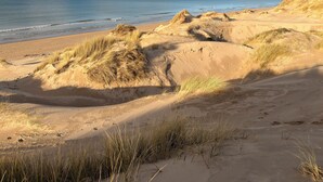 Une plage avec des dunes de sable et un ciel dégagé.