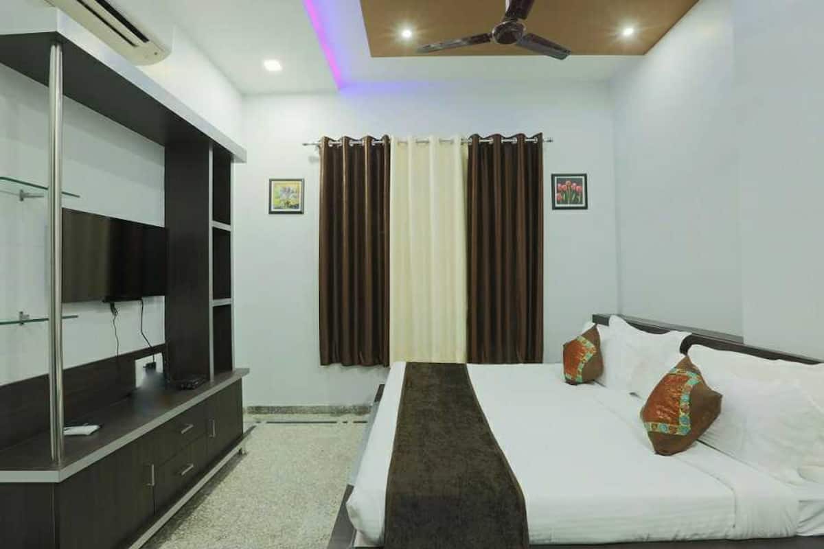 Una habitación de hotel con una cama, televisión, ventilador de techo y cortinas.