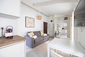 A modern living area with a sofa, a dining table, and a kitchen in the background. - A/C Studio in the Heart of Cannes - Old Port (Cannes)