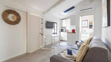 Una sala de estar moderna con un sofá, una televisión y una cocina con microondas.