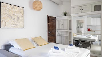 Habitación de hotel con cama, escritorio, silla, espejo y armario.