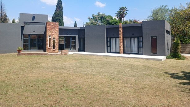 A modern building with a brick entrance, large windows, and a flat roof. - Room-serene Guest Room Retreat in Albert (Alberton)