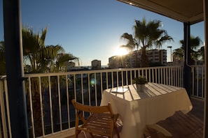 A balcony with a table and chairs, overlooking a cityscape with palm trees and buildings. - Lentiscares 212 by At Home Costa del Sol (Torrox)