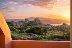A coastal landscape with rocky terrain, vegetation, and a distant cityscape. - Casa Audrey by Wonderful italy (Santa Teresa Gallura)