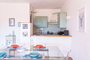 A compact kitchen with a dining area, featuring a tiled backsplash, a sink, and a countertop with various kitchen items. - Casa Audrey by Wonderful italy (Santa Teresa Gallura)