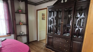 A room with a ceiling fan, a wooden cabinet with glass doors, a pink table, and a patterned rug. - The Borough Belle LLC -Spacious duplex in the heart of the historic district (Ebensburg)