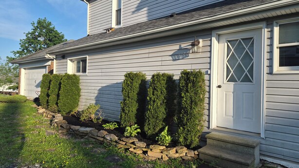 A house with a garage, a front door with a diamond pattern, and neatly trimmed hedges. - The Borough Belle LLC -Spacious duplex in the heart of the historic district (Ebensburg)