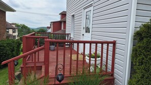 A wooden deck with a red railing, a white door, and a potted plant. - The Borough Belle LLC -Spacious duplex in the heart of the historic district (Ebensburg)