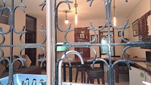 Ein Zimmer mit einem Metallgitter, einem Essbereich mit Stühlen und einem Tisch sowie einer Küchenzeile mit Geräten.