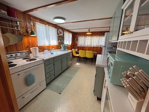 A compact kitchen with a stove, sink, and dining area. - Hickory Hill Hideaway! (Ogunquit)