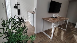 A modern kitchen with a built-in fridge, a wooden dining table, and a TV mounted on the wall. - NAUSICA (Saint-Jean-de-Monts)