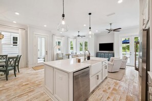 A spacious kitchen with a large island, white cabinetry, and a dining area with a table and chairs.