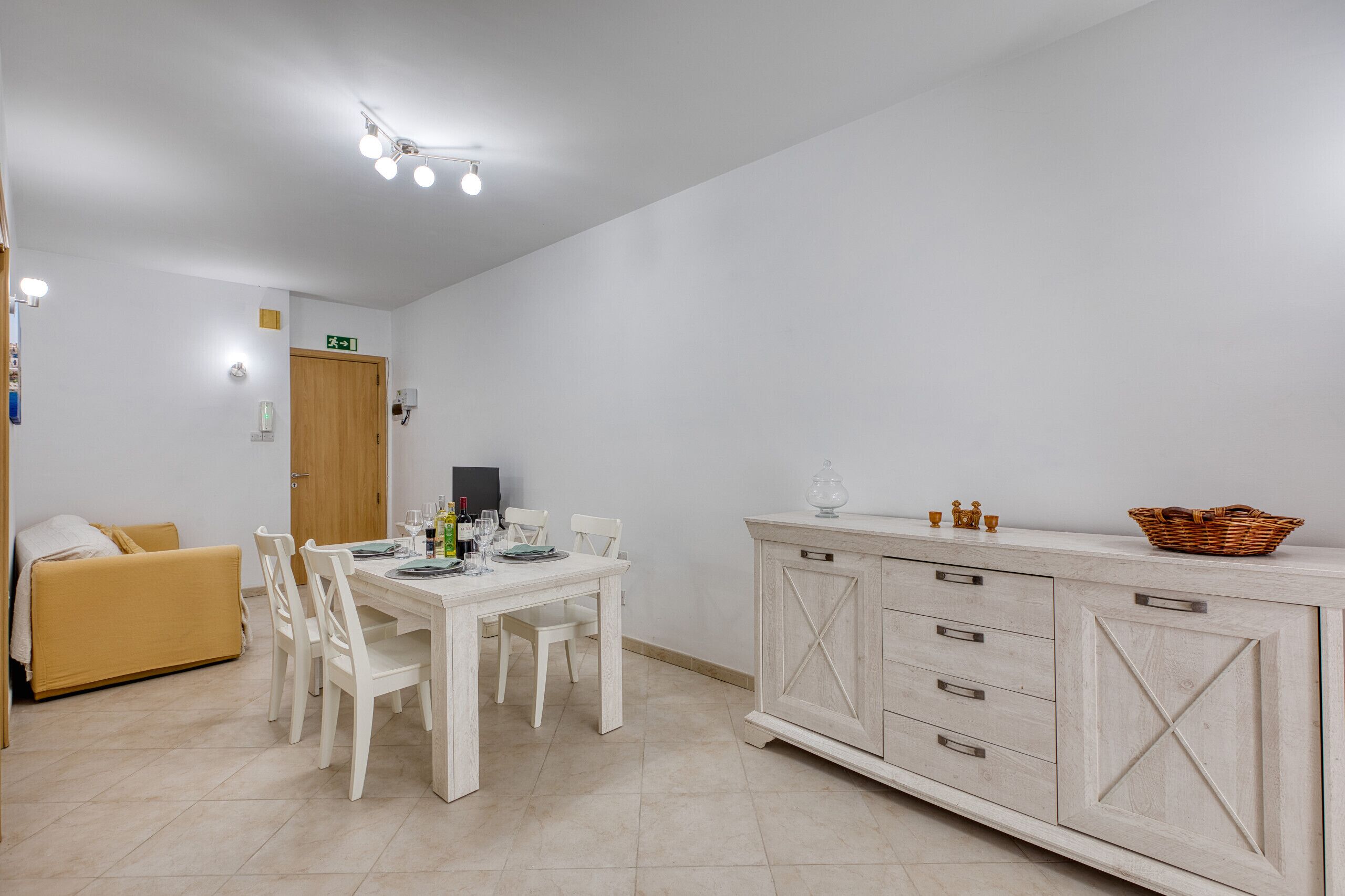 A dining area with a table, chairs, a cabinet, and a sofa.