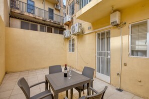 Eine kleine Terrasse im Freien mit Tisch und Stühlen, einer Weinflasche und zwei Weingläsern.