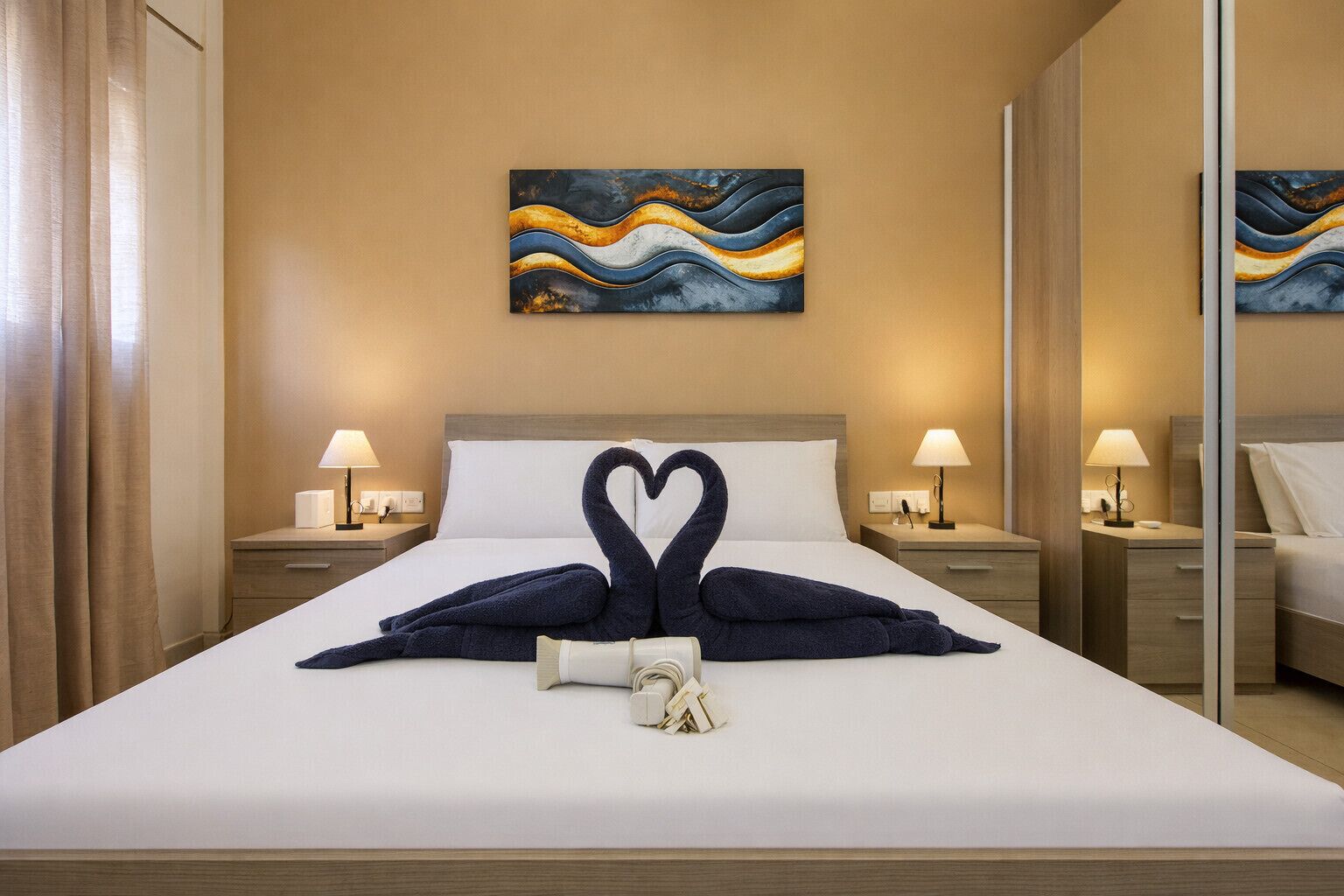 Ein Hotelzimmer mit einem Bett, zwei Nachttischen, Lampen, einem Bild an der Wand und einem Spiegel.