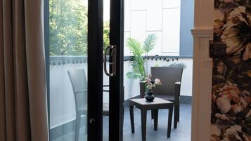 Habitación con puerta corrediza de vidrio que da a un espacio exterior con sillas de mimbre y una pequeña mesa.