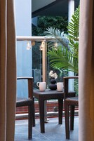 A balcony with wicker chairs, a table, and a potted plant.