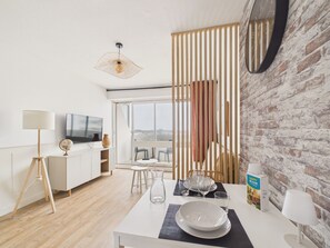 A modern living room with a dining area, a television, and a view of the city. - Sea view for 4 by the beach (Saint-Hilaire-de-Riez)