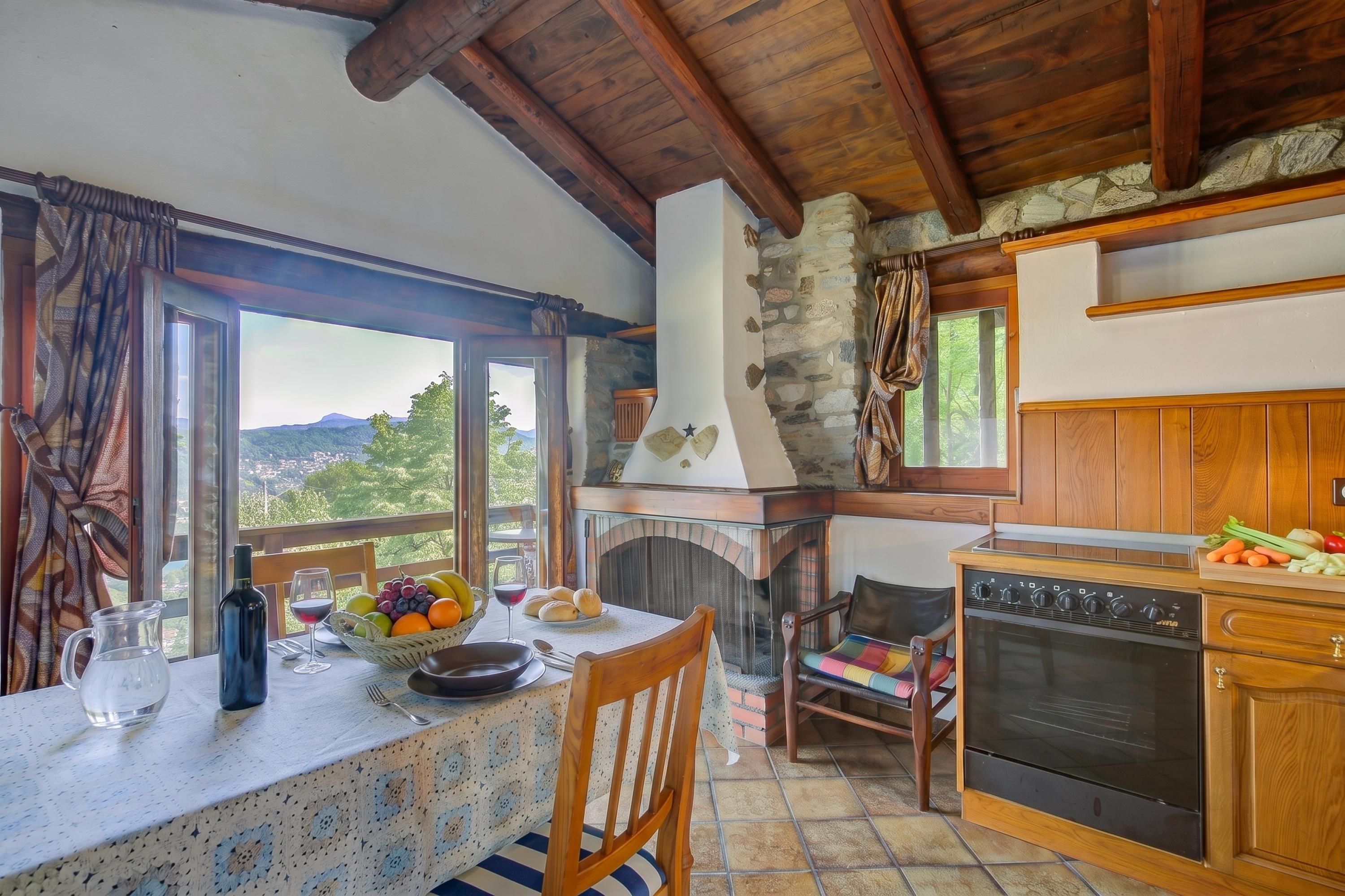 Una cocina rústica con chimenea de piedra, armarios de madera y un comedor con una mesa preparada para dos.