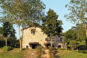 Un edificio de piedra con aspecto rústico, rodeado de árboles y vegetación.