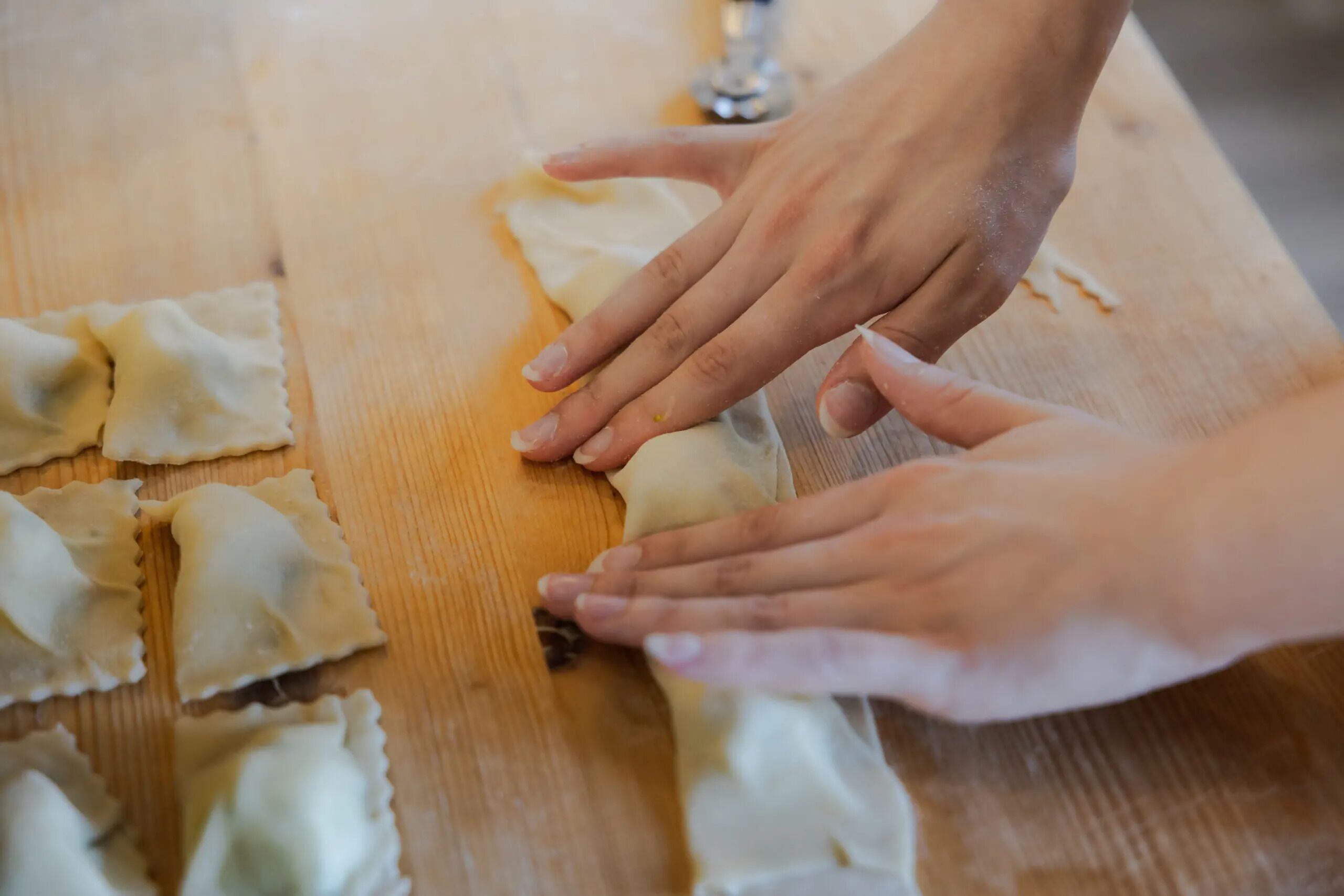 Hands preparing food on a wooden surface.