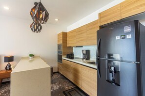 Eine moderne Küche mit einem schwarzen Kühlschrank, Holzschränken, einer eingebauten Mikrowelle und einer Pendelleuchte.