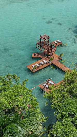 Una plataforma de madera flotante con una estructura central, rodeada de agua turquesa cristalina.
