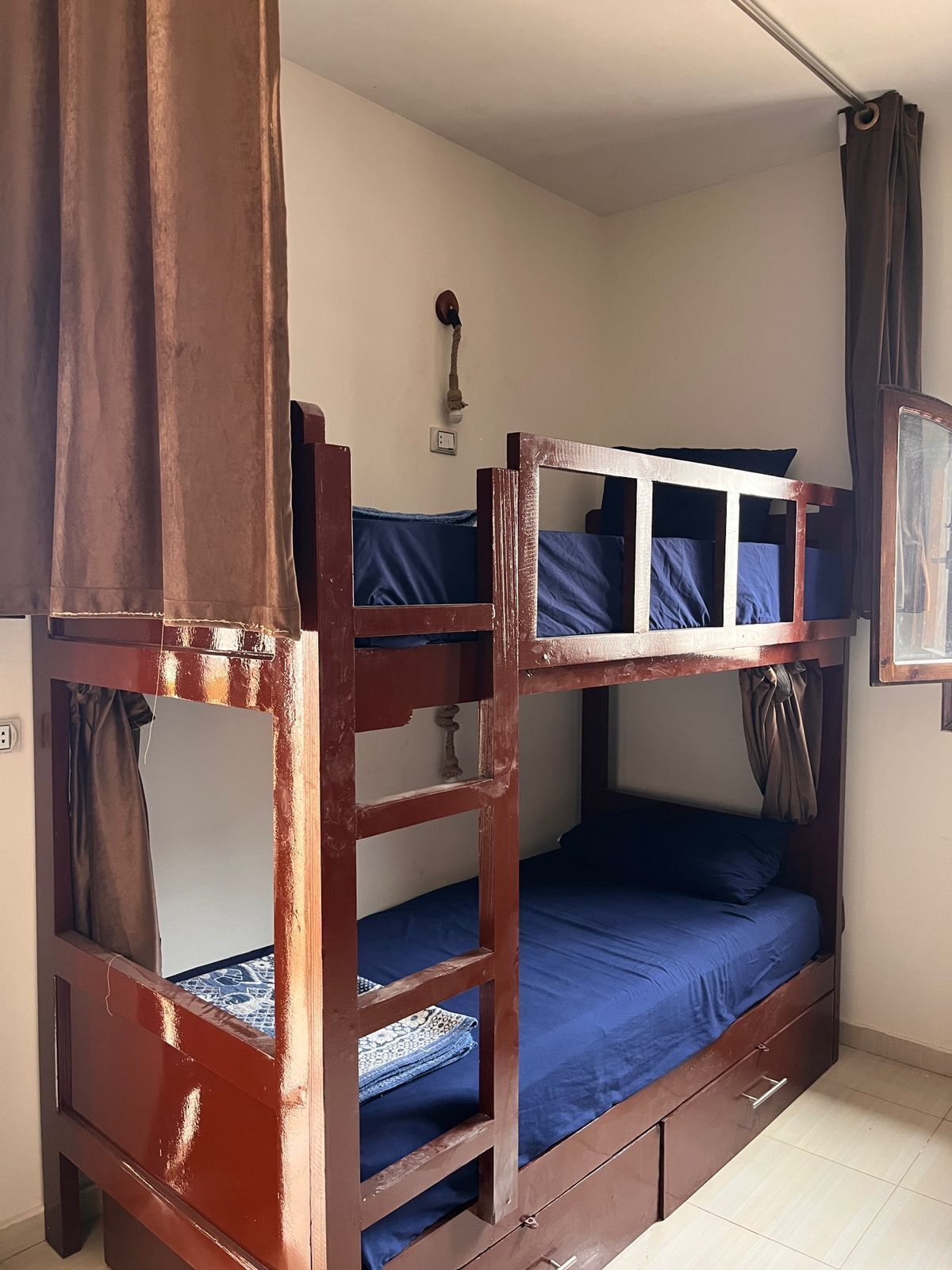 Una cama litera con dos niveles, una ventana pequeña y un aplique de pared.