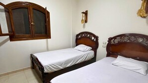 Une chambre avec deux lits en bois, une armoire et un appareil de climatisation.