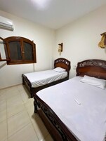 Una habitación con dos camas de madera, un armario y un aire acondicionado.