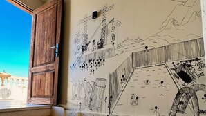 Un escalier avec une porte en bois, des murs de couleur beige et une fresque murale ornée de divers dessins.