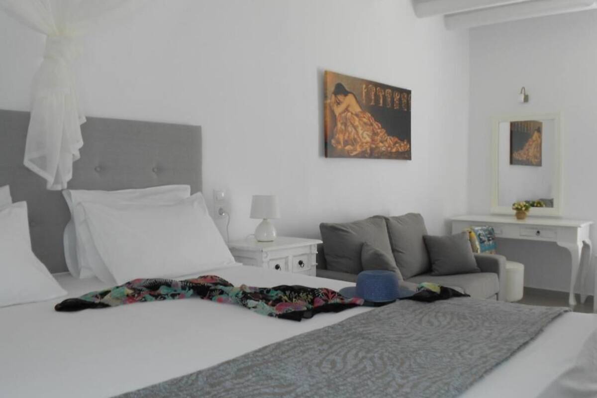 A hotel room with a bed, a nightstand, a desk, a chair, and a painting on the wall.