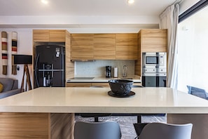 Eine moderne Küche mit Holzausstattung, einem schwarzen Kühlschrank, einer Mikrowelle und einer großen Kochinsel mit einer Schüssel.