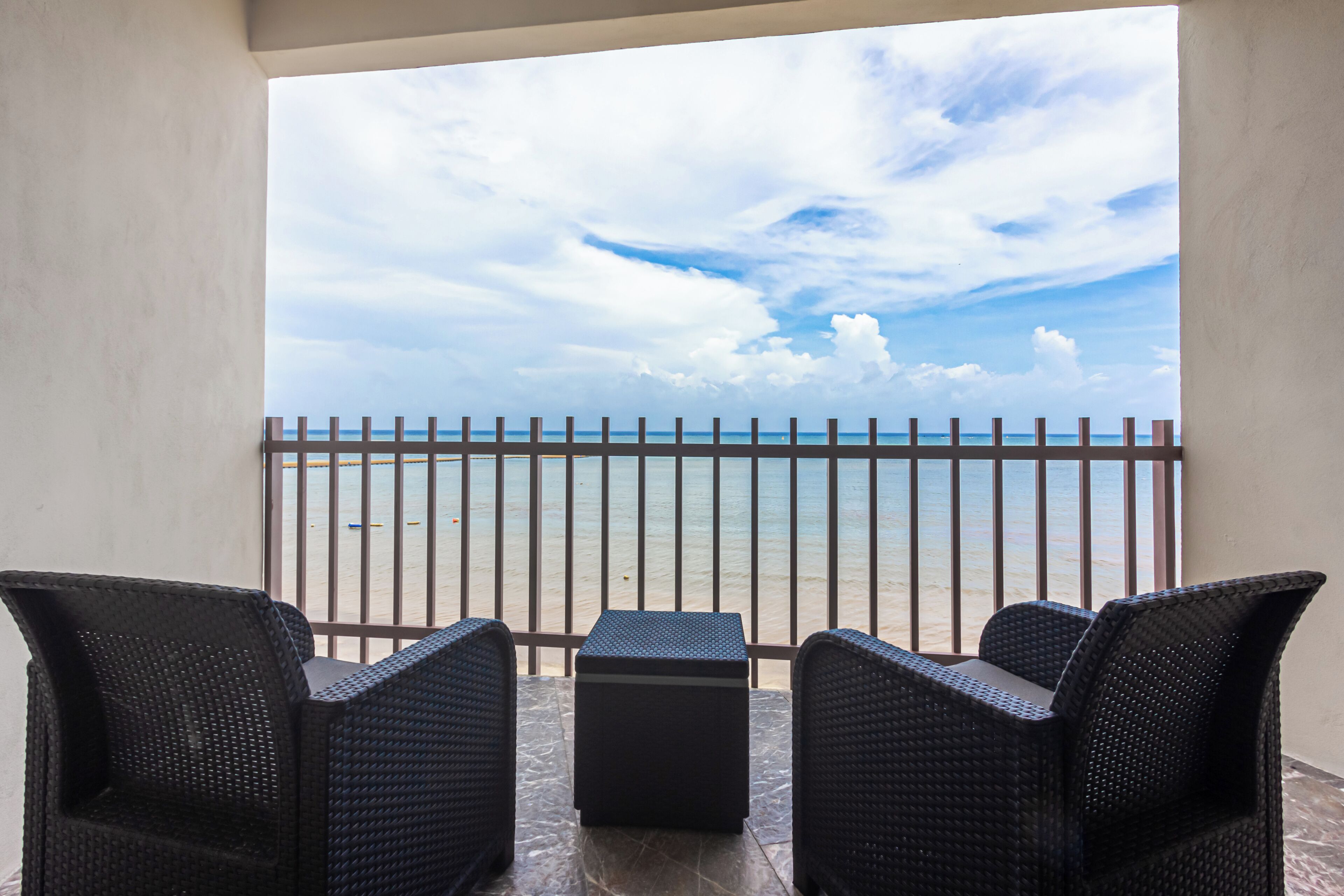 Een balkon met rieten meubilair en uitzicht op het strand.