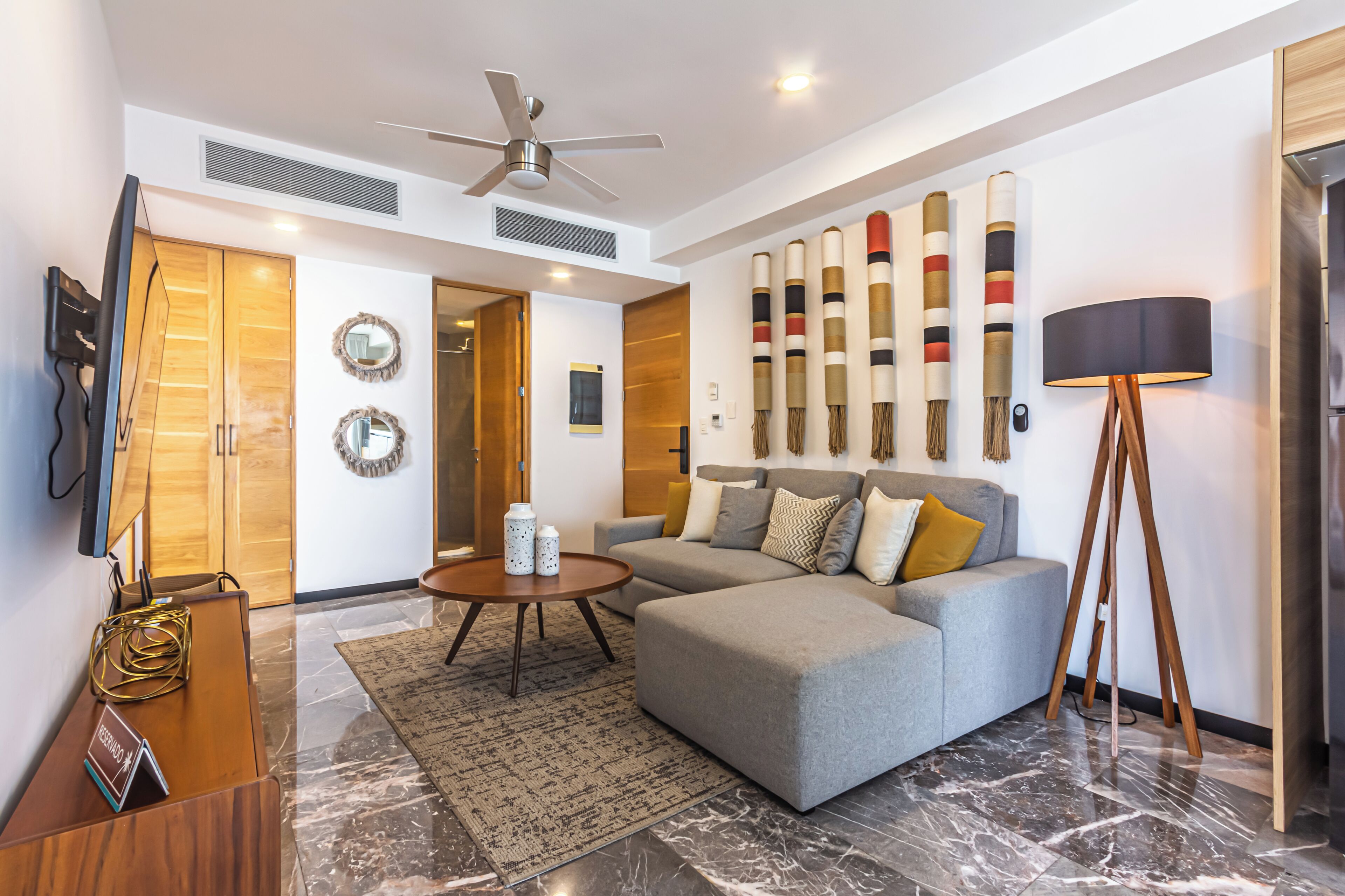 A modern living room with a grey sofa, a coffee table, a standing lamp, and a ceiling fan.