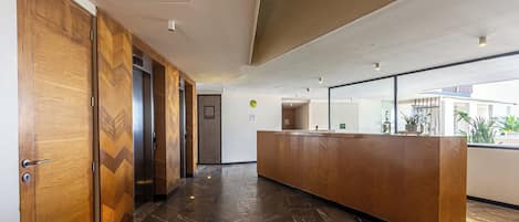 Una zona de recepción con un mostrador de madera, pared con diseño en chevron y suelo de baldosas.