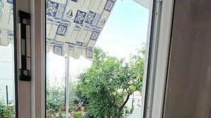 Una stanza con una porta scorrevole in vetro che dà su un'area esterna con un tendone a motivi e un patio piastrellato.