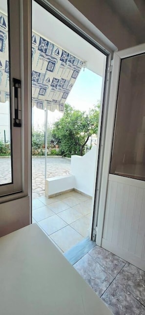 A room with a sliding glass door leading to an outdoor area with a patterned awning and a tiled patio. - PH Azure Horizon Residences G/1 (Sarandë)