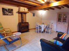 Ein gemütliches Wohnzimmer mit Kamin, einem Esstisch mit Stühlen, einer Couch und einem Schrank.