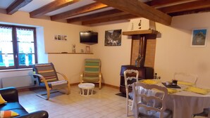 Ein gemütliches Wohnzimmer mit Kamin, Fernseher und Essbereich mit Stühlen und Tisch.