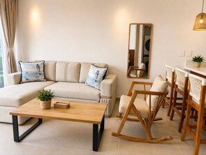 Ein stilvolles Wohnzimmer mit einer Couch, einem Couchtisch, Holzstühlen, einem Spiegel und einer Pendelleuchte.