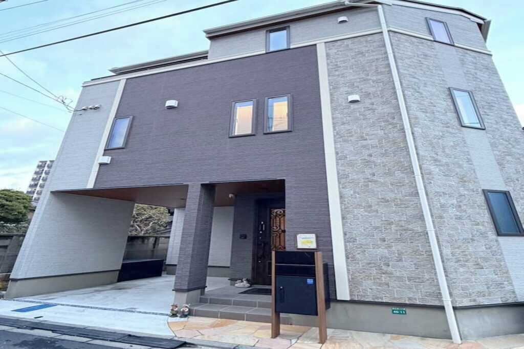 A modern two-story building with a flat roof, a covered entrance, and a small porch area.