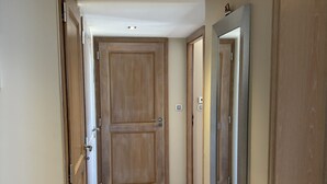 A hallway with wooden doors, a tiled floor, and a ceiling light. - Bay view Cavalaire sur Mer - Pretty T3 Air-conditioned Top floor Swimming pool Classified **** (Cavalaire sur Mer)