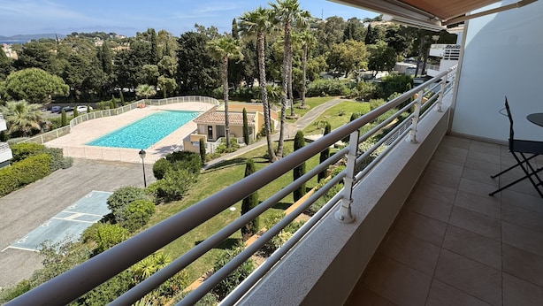 A balcony with a view of a swimming pool, surrounded by greenery and a residential area. - Bay view Cavalaire sur Mer - Pretty T3 Air-conditioned Top floor Swimming pool Classified **** (Cavalaire sur Mer)