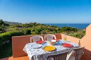 A table set for two with a view of the sea, surrounded by greenery and a clear sky. - Casa Audrey by Wonderful Italy (Santa Teresa di Gallura)