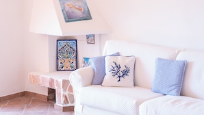 A white sofa with patterned cushions, a tiled floor, and a wall-mounted lamp. - Casa Audrey by Wonderful Italy (Santa Teresa di Gallura)