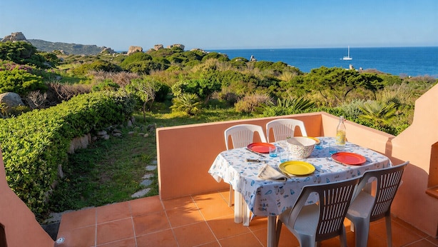 A terrace with a table set for four, overlooking a coastal landscape with vegetation and a clear sky. - Casa Audrey by Wonderful Italy (Santa Teresa di Gallura)