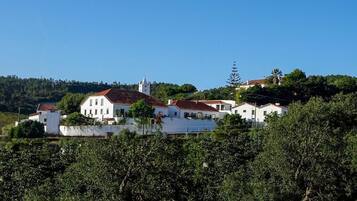 Uma aldeia situada numa encosta, com edifícios brancos, uma igreja e vegetação densa.