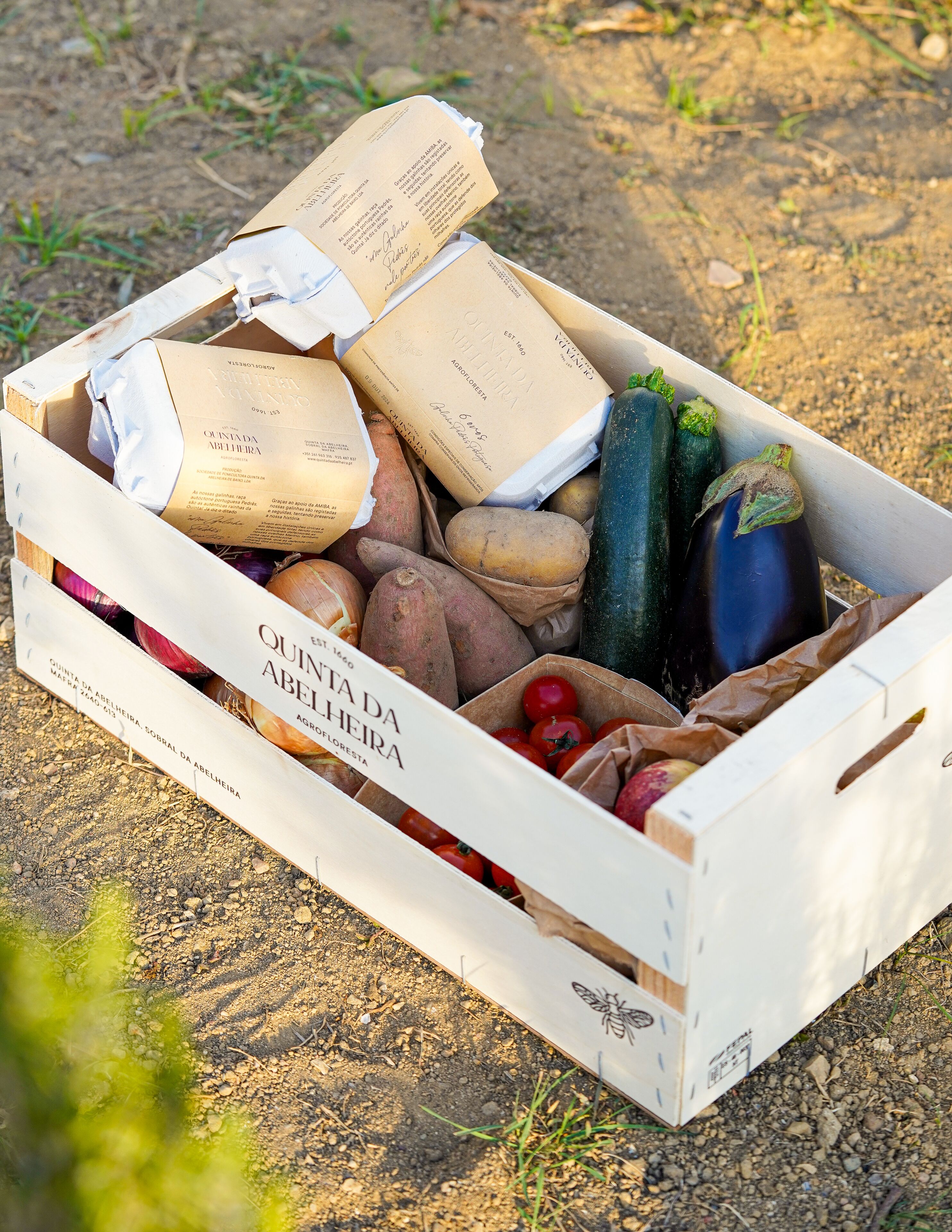 Caixa cheia de vários vegetais com a etiqueta 'Quinta da Abelheira'.