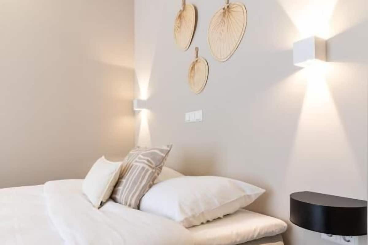 A bedroom with a bed, bedside table, and wall-mounted light fixtures.